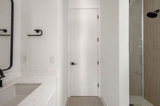 full bathroom with baseboards, tiled shower, and vanity