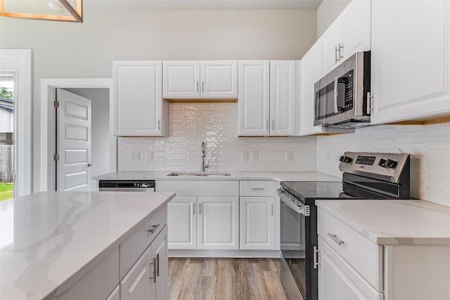 652 Aspen Ln, Cottonwood Shores, TX 78657 - kitchen with appliances with stainless steel finishes, white cabinetry, light stone countertops, light wood finished floors, and decorative backsplash