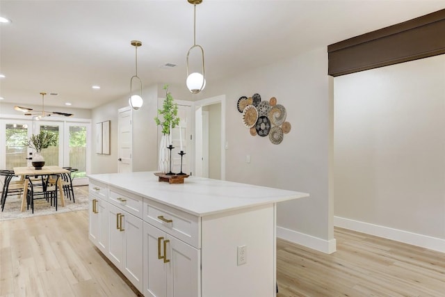6007 Belfast Dr, Austin, TX 78723 - kitchen featuring light wood-style floors, a center island, hanging light fixtures, white cabinets, and light countertops