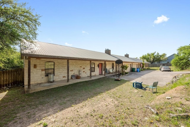 201 Loving Trl, Dripping Springs, TX 78620 - back of house with driveway, a chimney, metal roof, and a garage