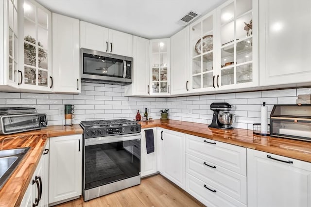 206 Quail Cir, Hutto, TX 78634 - kitchen featuring wooden counters, appliances with stainless steel finishes, white cabinets, and glass insert cabinets