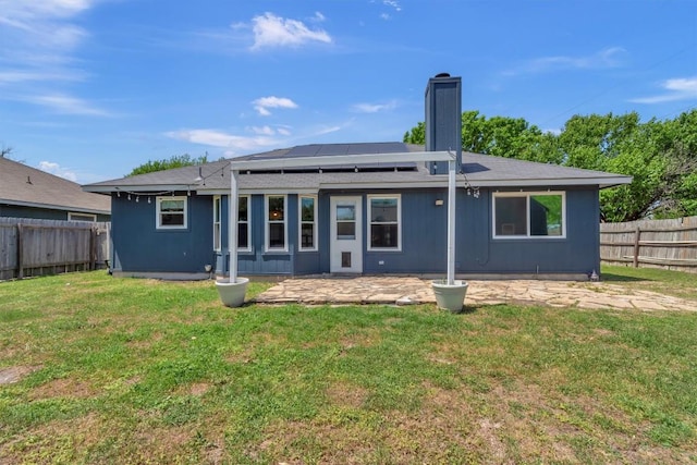 206 Quail Cir, Hutto, TX 78634 - rear view of house featuring roof mounted solar panels, a patio, and a chimney