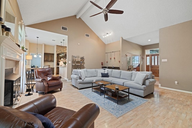7303 Bluntleaf Cv, Austin, TX 78750 - living area featuring a ceiling fan, light wood-type flooring, high vaulted ceiling, beamed ceiling, and a fireplace