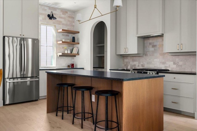 kitchen with freestanding refrigerator, open shelves, backsplash, a kitchen island, and dark countertops