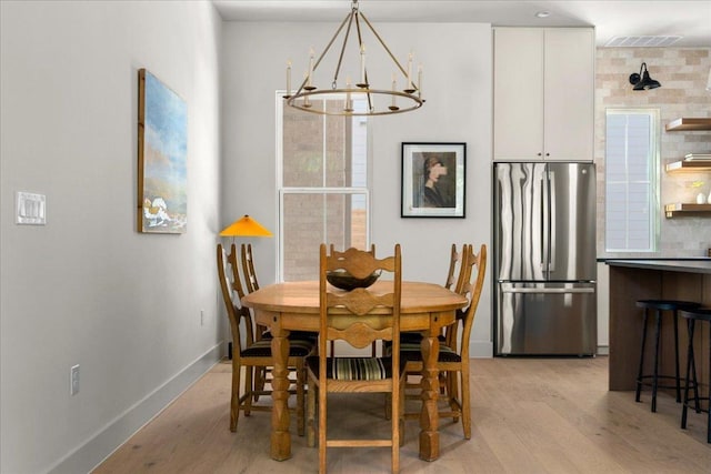 dining area featuring light wood-style floors, a chandelier, and baseboards