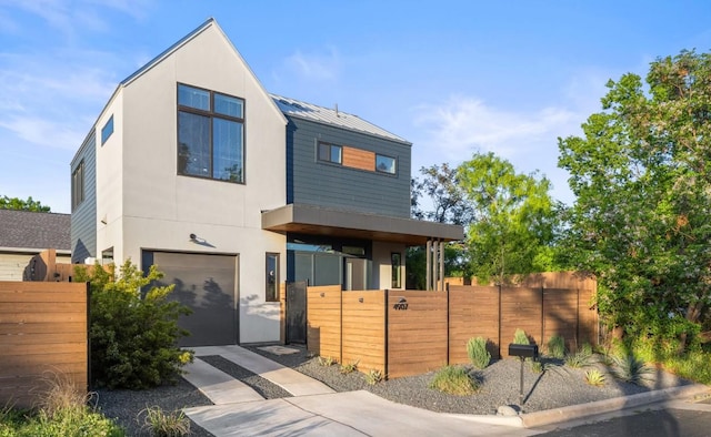 4907 Delores Ave, Austin, TX 78721 - contemporary house featuring a garage, stucco siding, metal roof, and driveway