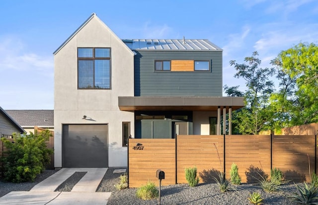 4907 Delores Ave, Austin, TX 78721 - modern home with an attached garage, concrete driveway, a standing seam roof, metal roof, and stucco siding