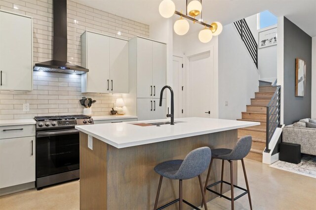 4907 Delores Ave, Austin, TX 78721 - kitchen featuring stainless steel gas range, wall chimney range hood, a sink, backsplash, and light countertops