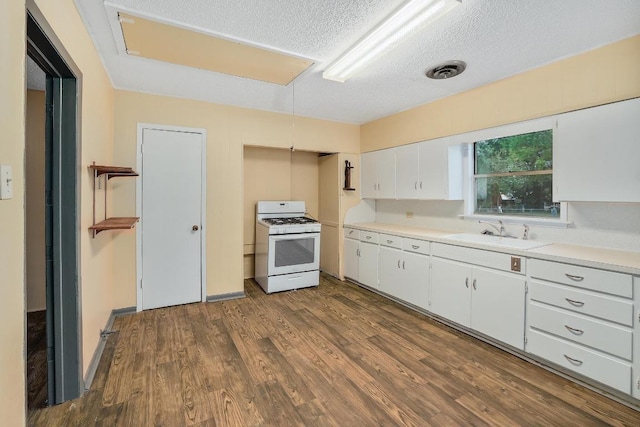 300 W Cleveland St, Elgin, TX 78621 - kitchen with white range with gas stovetop, a textured ceiling, dark wood finished floors, white cabinets, and light countertops