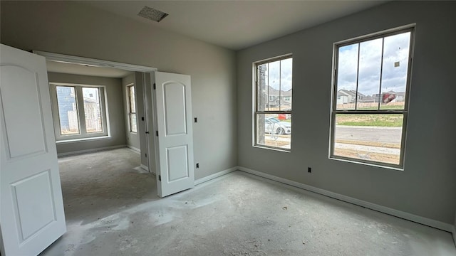 unfurnished room with baseboards, a wealth of natural light, and concrete floors