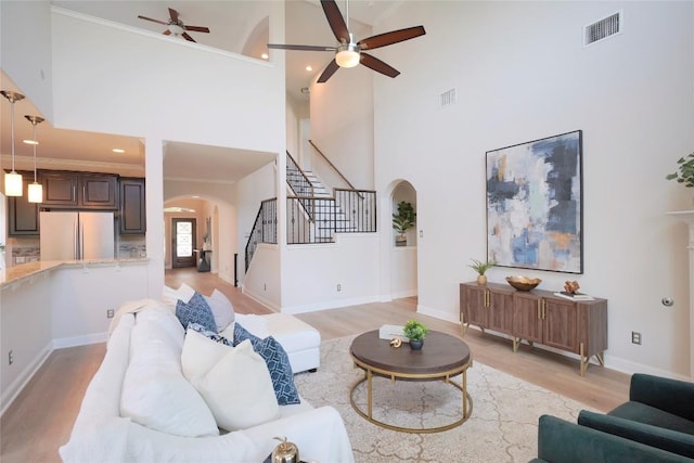 11721 Quintana Cv, Austin, TX 78739 - living area with arched walkways, ceiling fan, stairway, a towering ceiling, and light wood-style floors