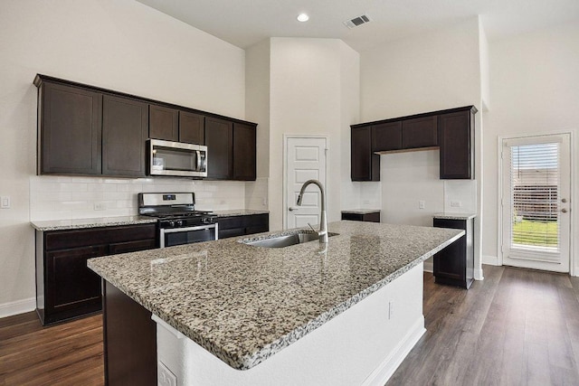 kitchen with appliances with stainless steel finishes, light stone countertops, baseboards, and a sink