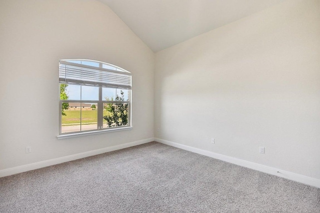 carpeted spare room featuring vaulted ceiling and baseboards