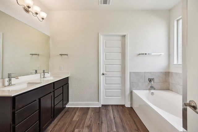 full bathroom with baseboards, wood finished floors, a bath, and a sink
