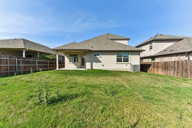 rear view of house with a fenced backyard, a yard, and stucco siding