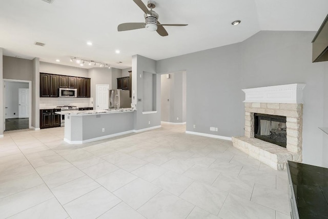2616 Glenwood Trl, Cedar Park, TX 78613 - unfurnished living room featuring a ceiling fan, a fireplace with raised hearth, light tile patterned floors, track lighting, and baseboards