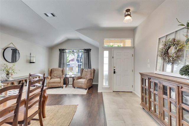foyer entrance featuring visible vents, light wood finished floors, and lofted ceiling