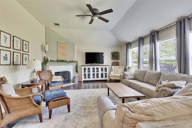 living area featuring a ceiling fan, visible vents, a fireplace with flush hearth, wood finished floors, and lofted ceiling