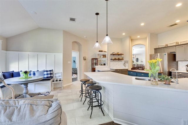 kitchen featuring arched walkways, a kitchen breakfast bar, freestanding refrigerator, and visible vents
