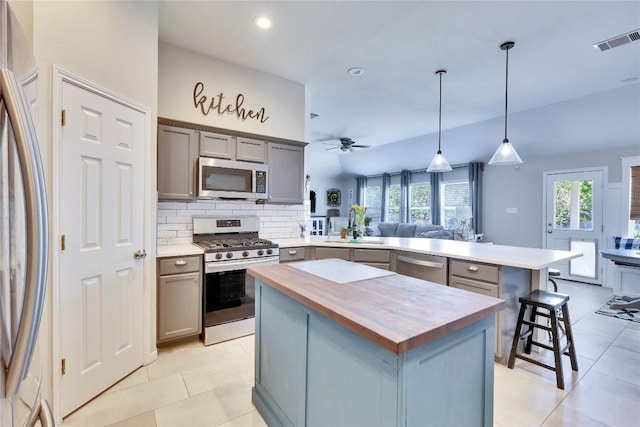 kitchen with gray cabinetry, appliances with stainless steel finishes, butcher block countertops, and visible vents