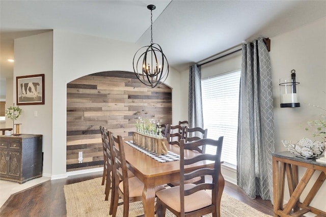 dining room featuring arched walkways, a notable chandelier, a wealth of natural light, and wood finished floors
