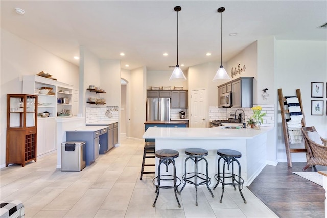kitchen with appliances with stainless steel finishes, a sink, a breakfast bar area, a peninsula, and decorative backsplash