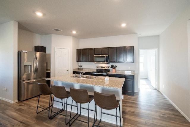 kitchen with stainless steel appliances, a breakfast bar area, dark wood-type flooring, and a sink
