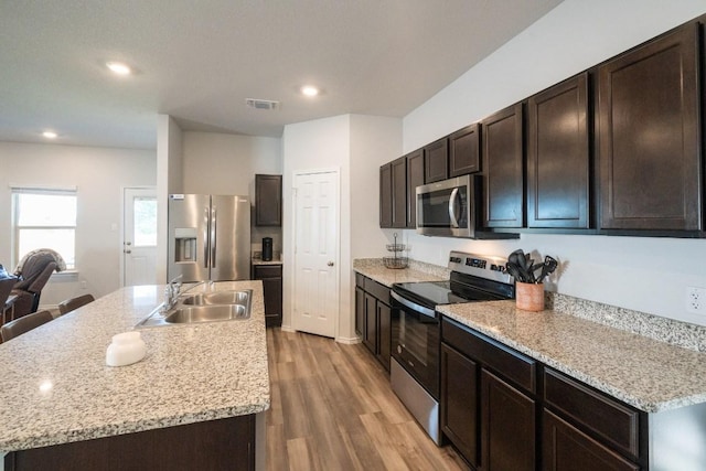 kitchen featuring visible vents, a sink, appliances with stainless steel finishes, light wood-style floors, and dark brown cabinets