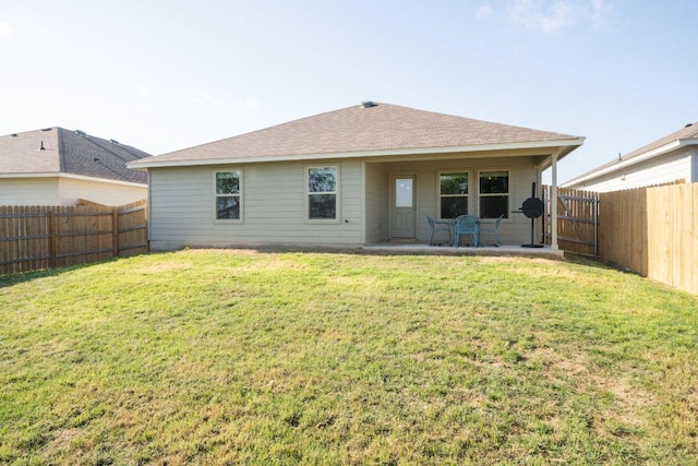 back of house with a shingled roof, a fenced backyard, a patio area, and a lawn