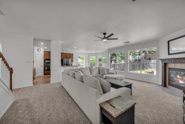 1107 Shiloh St, Cedar Park, TX 78613 - living area with light colored carpet, recessed lighting, a tile fireplace, a ceiling fan, and stairs