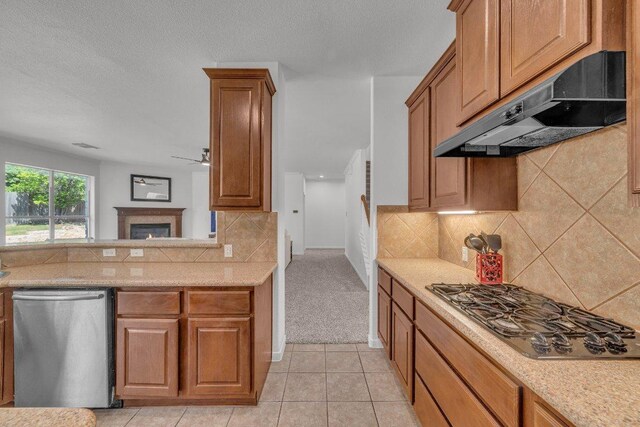 1107 Shiloh St, Cedar Park, TX 78613 - kitchen with stainless steel dishwasher, under cabinet range hood, black gas stovetop, backsplash, and brown cabinets