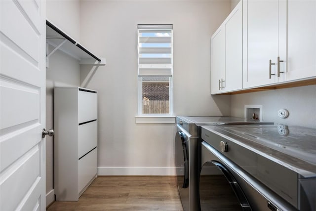 laundry room featuring washer and dryer, cabinet space, light wood-style floors, and baseboards