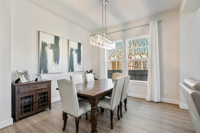 dining room with light wood finished floors, a chandelier, and baseboards