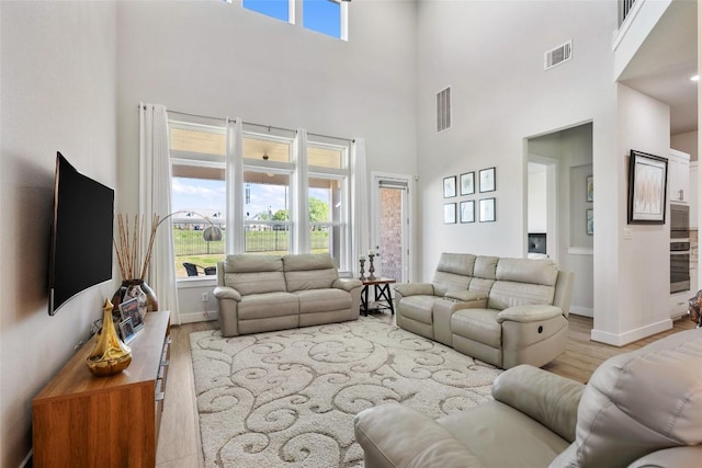 living room with wood finished floors, a towering ceiling, and baseboards