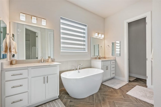 full bathroom featuring two vanities and a freestanding tub