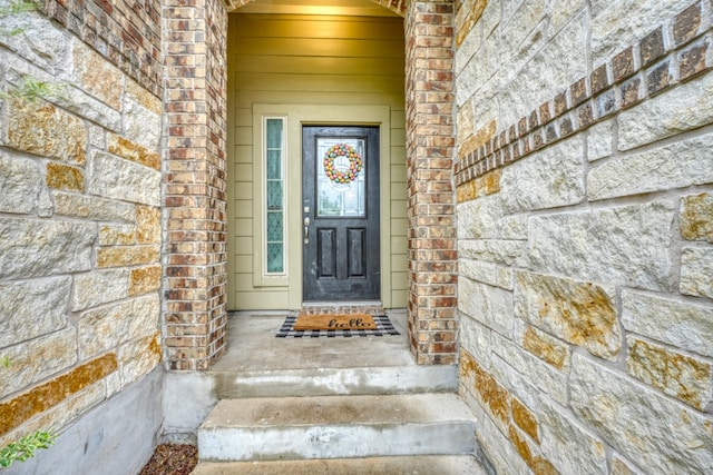 entrance to property featuring stone siding and brick siding