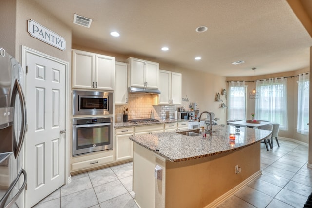 5917 Moriano Cv, Round Rock, TX 78665 - kitchen featuring stainless steel appliances, a sink, under cabinet range hood, light tile patterned flooring, and backsplash
