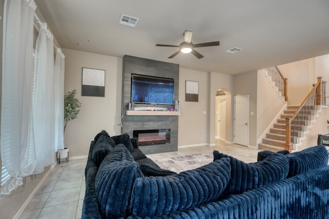 5917 Moriano Cv, Round Rock, TX 78665 - living room with ceiling fan, light tile patterned floors, a large fireplace, stairs, and arched walkways