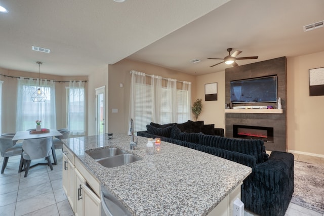 5917 Moriano Cv, Round Rock, TX 78665 - kitchen featuring white cabinets, light stone countertops, light tile patterned flooring, a large fireplace, and a ceiling fan