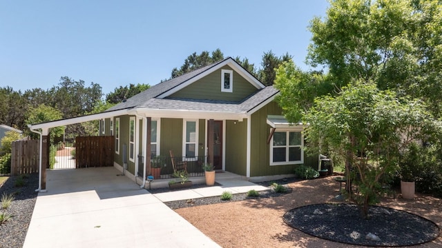 view of front facade with a carport, roof with shingles, driveway, fence, and covered porch
