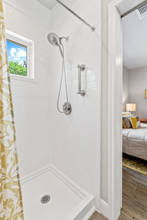 bathroom with visible vents, tiled shower, and wood finished floors