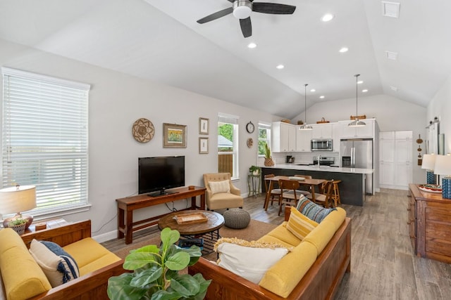 living room with lofted ceiling, baseboards, light wood-type flooring, visible vents, and ceiling fan