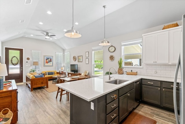 kitchen with vaulted ceiling, stainless steel refrigerator, open floor plan, light wood finished floors, and a sink