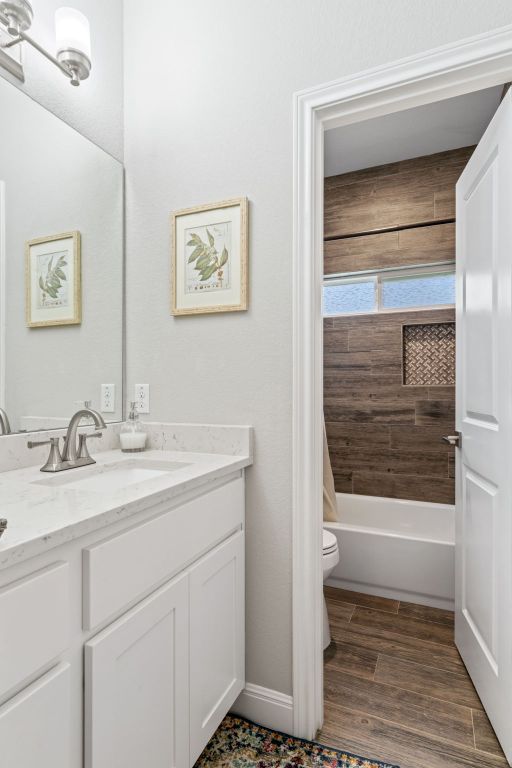 full bathroom featuring toilet, wood finished floors, vanity, and shower / washtub combination