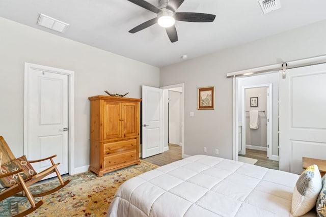 bedroom with baseboards, connected bathroom, visible vents, and a barn door