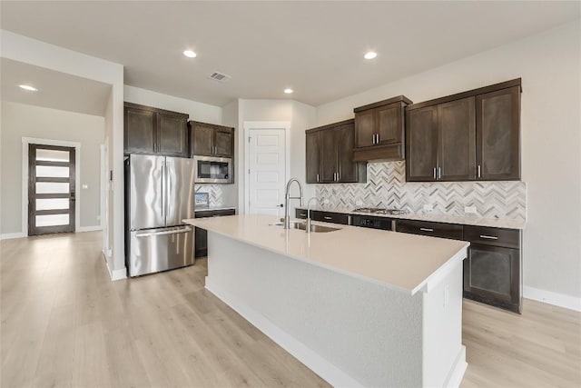 508 Saturnia Cv, Georgetown, TX 78628 - kitchen with stainless steel appliances, a sink, light wood-style floors, dark brown cabinets, and recessed lighting