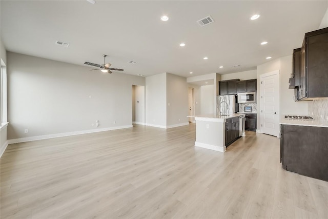 508 Saturnia Cv, Georgetown, TX 78628 - kitchen featuring appliances with stainless steel finishes, open floor plan, a kitchen island with sink, dark brown cabinetry, and light countertops