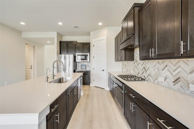 508 Saturnia Cv, Georgetown, TX 78628 - kitchen with a sink, appliances with stainless steel finishes, light wood finished floors, light countertops, and decorative backsplash