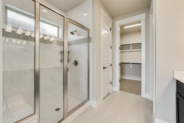 508 Saturnia Cv, Georgetown, TX 78628 - full bath with a stall shower, vanity, a walk in closet, baseboards, and tile patterned flooring