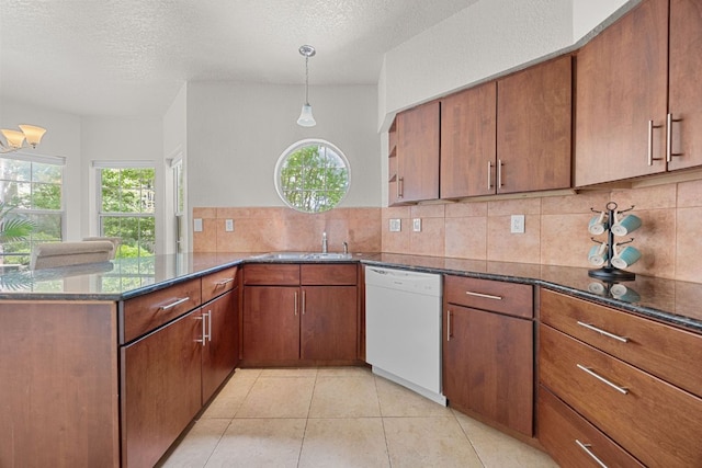 kitchen with dark stone countertops, backsplash, a peninsula, and dishwasher